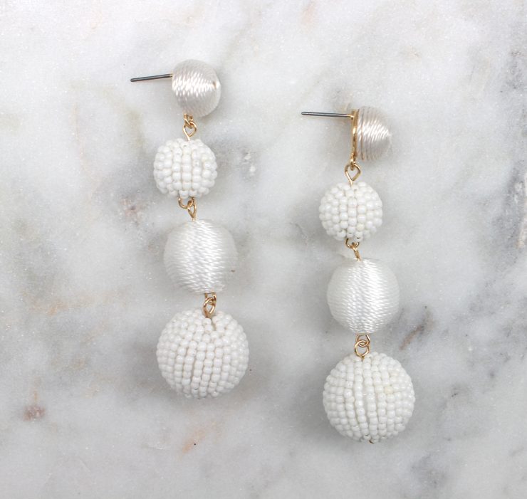 A photo of the Shimmer Thread Wrap Ball Earrings product