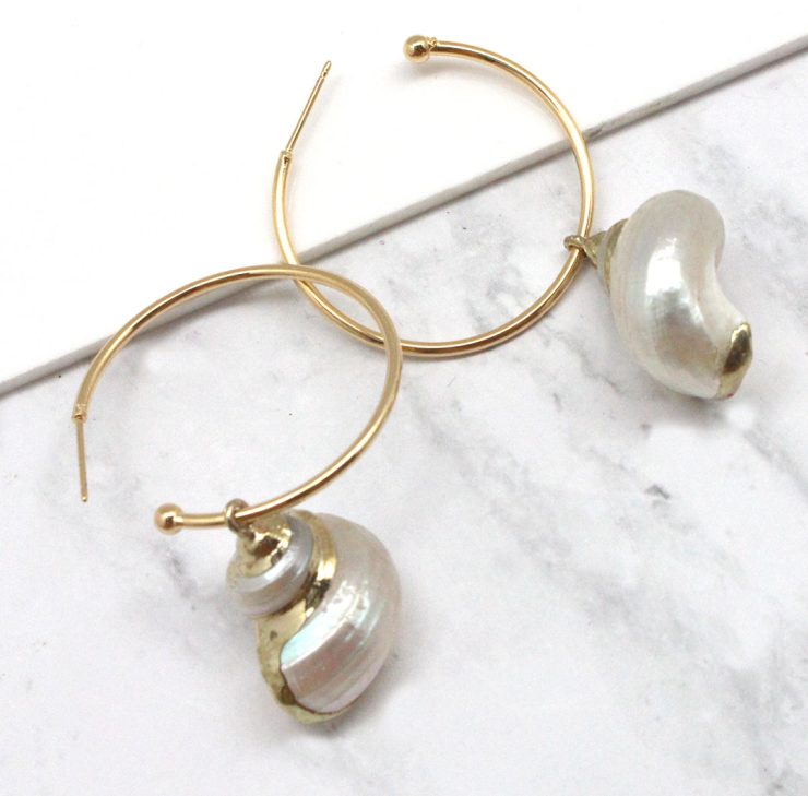 A photo of the Turbo Shell Hoop Earrings product